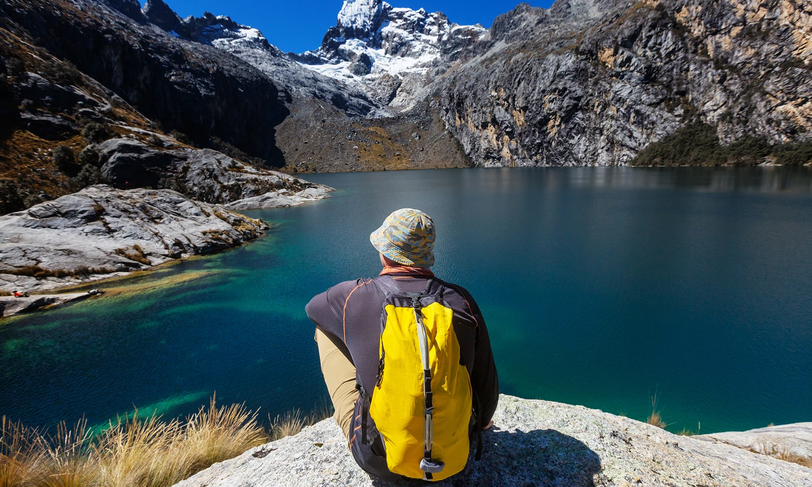 Tranquil lake reflecting a clear blue sky and snow-capped mountains during the Ausangate Lakes Expedition, Cusco, Peru, Kaymara Luxury Travel.