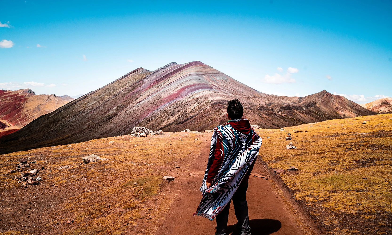Tranquil lake surrounded by lush green hills and wildflowers in the Peruvian Andes, Kaymara Luxury Travel.