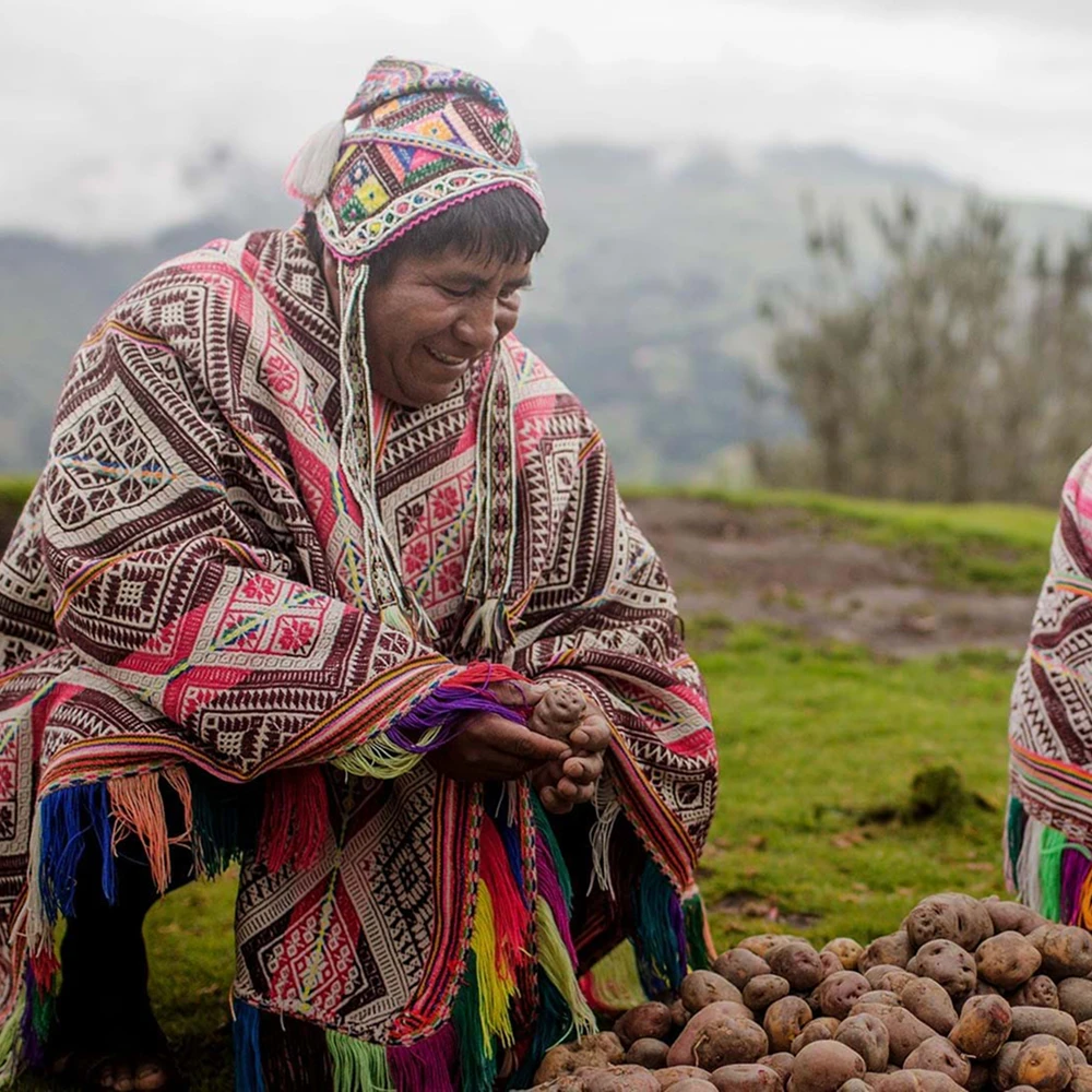 Vibrant street market scene with colorful produce and community interaction in the Potato Park, Cusco, Peru, Kaymara Luxury Travel.